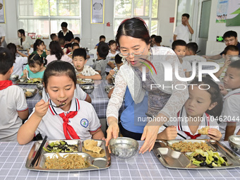 A teacher serves hot water to a student at Yanghe Primary School in Gaoliu town, Qingzhou city, East China's Shandong province, Sept 4, 2023...