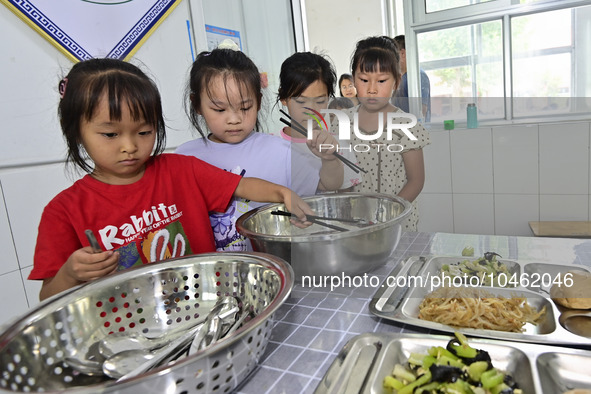 Students receive cutlery for lunch at Yanghe Primary School in Gaoliu town, Qingzhou city, East China's Shandong province, Sept 4, 2023. 