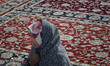 A veiled Afghan refugee woman looks on as she sits at a holy shrine while taking part in a...