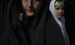 A young veiled Iranian girl looks on as she stands at a holy shrine during a religious cer...
