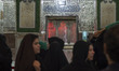 Shi'ite pilgrims walk past a tomb at a holy shrine while taking part in a religious ceremo...