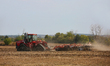 Farmer uses a machine to till farmland after crops have been harvested in Markham, Ontario...