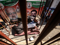 A Palestinian man holds a placard reading in Arabic: "I am on hunger strike for the prisoners" inside an iron cage as he stages a protest in...