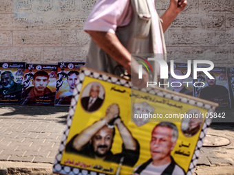 Palestinian man walks in front of pictures of Palestinian prisoners , which stages a protest in solidarity with Palestinian prisoners on hun...