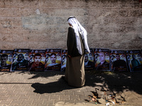 Palestinian man walks in front of pictures of Palestinian prisoners , which stages a protest in solidarity with Palestinian prisoners on hun...