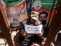A Palestinian man holds a placard reading in Arabic: "I am on hunger strike for the prisoners" inside an iron cage as he stages a protest in...