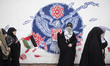 A veiled Iranian schoolgirl flashes a Victory sign while standing in front of an anti-U.S....