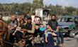 Palestinians fleeing Gaza City and other parts of northern Gaza, carry some belongings as...
