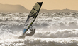 A surfer is facing the strong south-westerly wind near Quagliodromo Beach with the city of...