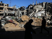 Palestinians are walking in front of Al-Maghazi bakery, which was destroyed in an Israeli strike earlier this month, in Al-Maghazi camp in t...