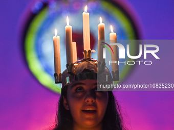 A worshipper is wearing a crown of candles to represent Saint Lucia as she leads a St. Lucia's Day celebration at the Evangelical Lutheran C...
