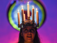 A worshipper is wearing a crown of candles to represent Saint Lucia as she leads a St. Lucia's Day celebration at the Evangelical Lutheran C...