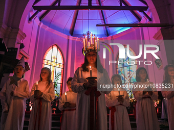 Youths are holding candles as they perform during the celebration of St. Lucia's Day, an annual Swedish celebration symbolizing light in the...