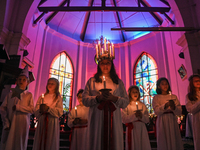 Youths are holding candles as they perform during the celebration of St. Lucia's Day, an annual Swedish celebration symbolizing light in the...