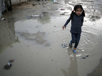 A Palestinian girl is standing amidst the rain at a camp for displaced people in Deir El-Balah, in the central Gaza Strip, where many civili...