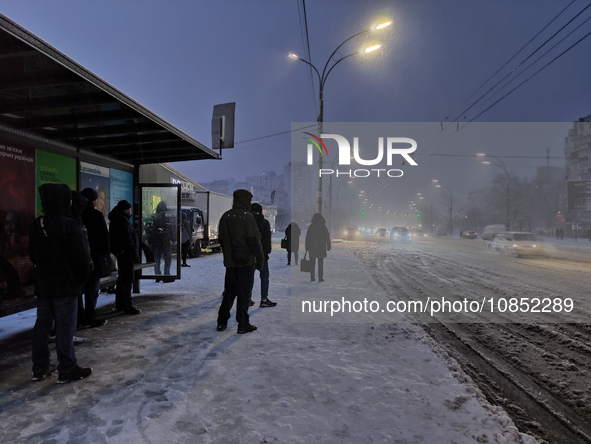 People are waiting at a public transport stop during a snowfall in Kyiv, Ukraine, on December 14, 2023. 