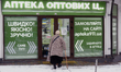 A senior woman with a walking cane is entering a chemist in winter in Kyiv, Ukraine, on De...