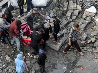 Palestinians are carrying a person who has been pulled out from the rubble of a building following Israeli strikes on the al-Maghazi refugee...