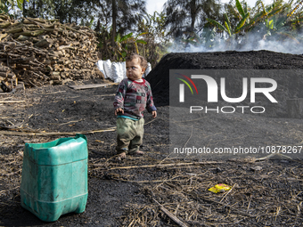 A child of an Egyptian laborer is playing beside piles of charcoal in Al Bostan, Beheira Governorate, Egypt, on December 17, 2023.  (