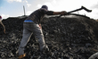 An Egyptian laborer is collecting charcoal with his bare hands at the charcoal factory in...