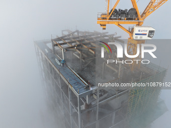 Workers are working on the 416.6-meter-high Hexi City II roof in heavy fog in Nanjing, Jiangsu Province, China, on December 29, 2023. (