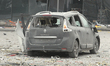A car is being seen destroyed outside a shopping mall that is damaged in the massive Russi...