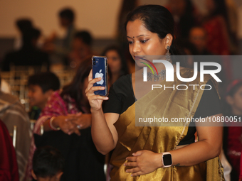 A Bengali Hindu woman is taking a photo of the idol of Goddess Durga during the Durga Puja festival at a pandal in Mississauga, Ontario, Can...
