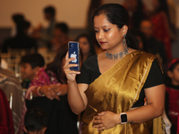 A Bengali Hindu woman is taking a photo of the idol of Goddess Durga during the Durga Puja festival at a pandal in Mississauga, Ontario, Can...