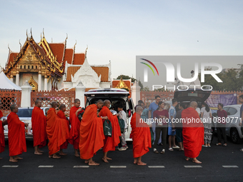People are making merit by offering food to a Buddhist monk during the morning alms ahead of New Year's Eve outside Wat Benchamabopitr in Ba...