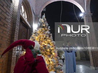 An Iranian clergyman is ringing the church bell to mark the arrival of the New Year while standing next to a Christmas tree at the Saint Tar...