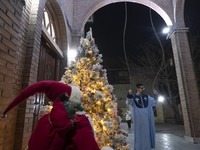 An Iranian clergyman is ringing the church bell to mark the arrival of the New Year while standing next to a Christmas tree at the Saint Tar...