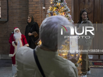 Iranian-Christian women are posing for photographs with a statue of Santa Claus and a Christmas tree at the Saint Targmanchats Church in eas...