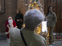 Iranian-Christian women are posing for photographs with a statue of Santa Claus and a Christmas tree at the Saint Targmanchats Church in eas...