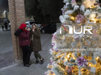 Two Iranian-Christian women are standing together next to a Christmas tree at the Saint Targmanchats Church in eastern Tehran, during a New...
