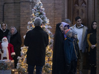 A veiled Iranian woman is standing next to a Christmas tree at the Saint Targmanchats Church in eastern Tehran with her relatives, during a...