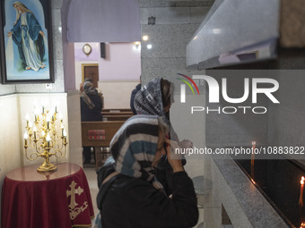 Two Iranian-Christian women are praying after lighting candles at the Saint Targmanchats Church in eastern Tehran, during a New Year mass pr...