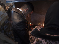 An Iranian-Christian man is praying after lighting candles at the Saint Targmanchats Church in eastern Tehran, during a New Year mass prayer...