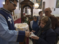 Iranian-Christian people are receiving holy bread at the Saint Targmanchats Church in eastern Tehran, after a New Year mass prayer ceremony,...