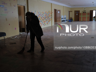 An employee is sweeping glass shards and rubble in the corridor at school N221, which was damaged during the Russian missile attack, in Kyiv...