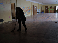An employee is sweeping glass shards and rubble in the corridor at school N221, which was damaged during the Russian missile attack, in Kyiv...