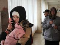 A woman is holding a dog and talking on the phone in the corridor at school N221, which was damaged in the Russian missile attack, in Kyiv,...