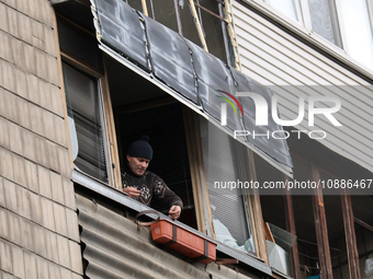 Residents are removing shards of window glass from the balcony of their apartment in the Dorohozhychi district, which was broken by a Russia...