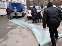 Residents are receiving film to repair windows broken by Russian rocket fire in an apartment building in the Dorohozhychi district of Kyiv,...