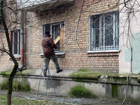 A man is using plywood to cover a window that was broken by a Russian missile attack on an apartment block in Dorohozhychi, Kyiv, Ukraine, o...