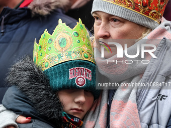 A boy and his grandmother, wearing a paper crown participate in a public Nativity Play performed on the street of Old Town of Krakow, Poland...