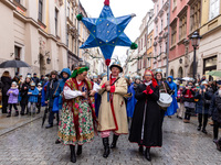 A crowd, wearing paper crowns and regional clothes follow a man with a star as they participate in a public Nativity Play performed on the s...