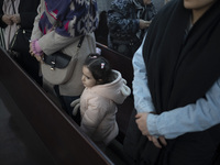 A young girl is standing next to Iranian-Armenian worshippers who are praying at the St. Vartan Armenian Church in central Tehran during a C...