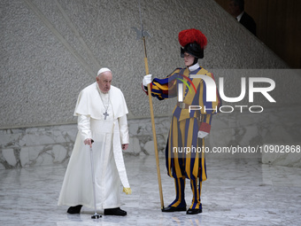 Pope Francis is walking past a member of the Pontifical Swiss Guard using a cane as he arrives to lead his weekly general audience in the Pa...