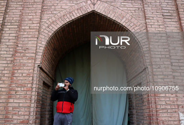 A man is taking pictures with his mobile phone as Kashmiris offer special prayers (not in picture) in the compound of Jamia Masjid, or Grand...