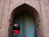 A man is taking pictures with his mobile phone as Kashmiris offer special prayers (not in picture) in the compound of Jamia Masjid, or Grand...